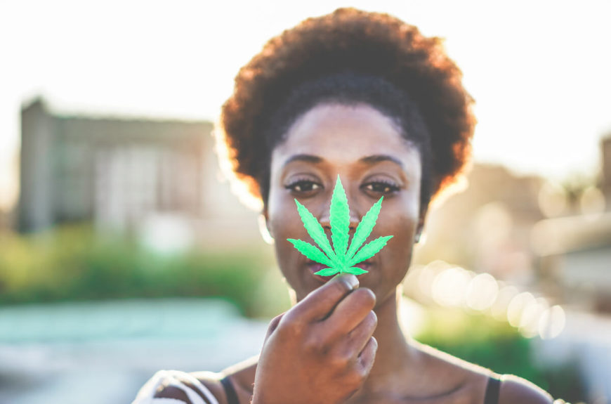 A woman holding a CBD cannabis leaf.
